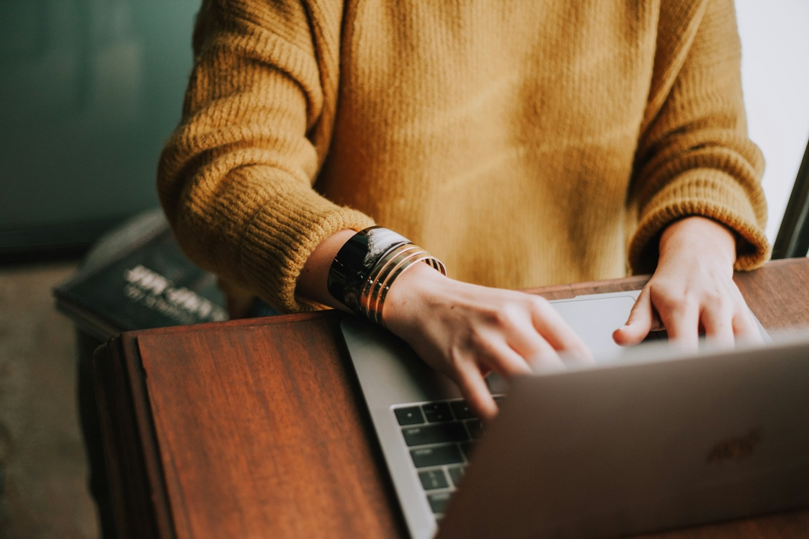 A creator typing on a laptop at a wooden desk